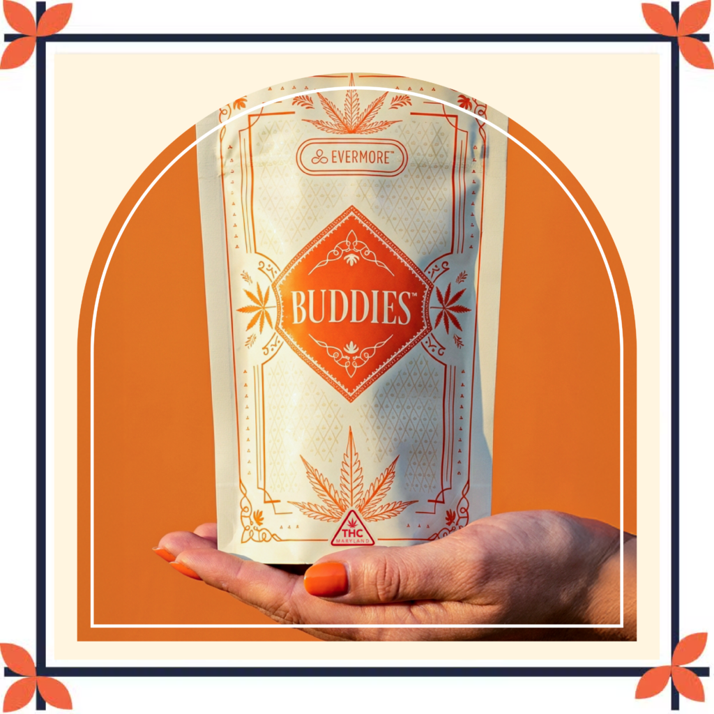 A hand with bright orange nail polish holds a cannabis vape cartridge beside an Evermore Concentrations premium concentrates package. The package features a cream-colored background with a gold dripping concentrate design and gold lettering. The image is set against a vibrant orange backdrop and framed with a cream and navy border accented by orange floral corner details, creating a retro-inspired aesthetic.
